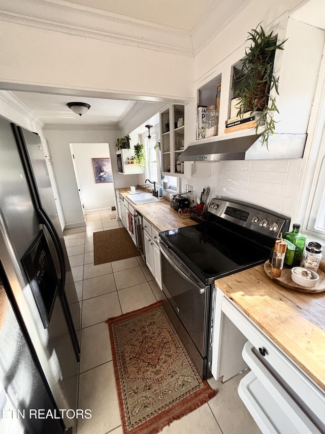 kitchen featuring backsplash, wooden counters, crown molding, appliances with stainless steel finishes, and a sink