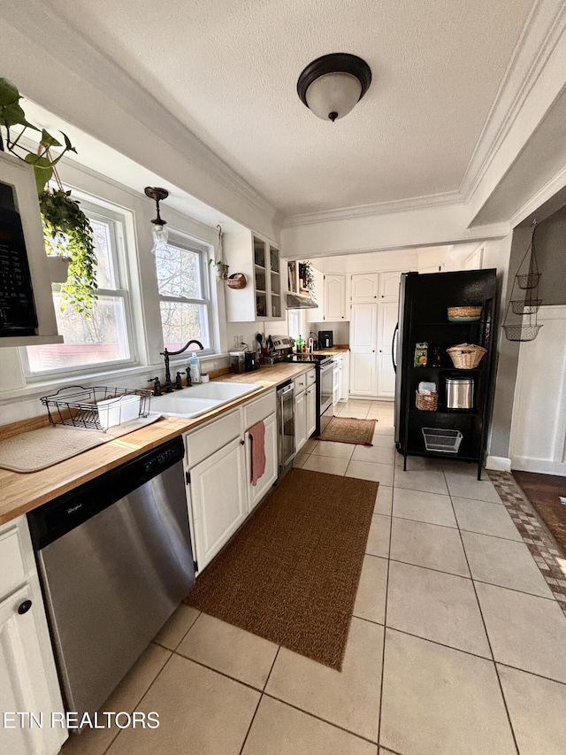 kitchen featuring crown molding, appliances with stainless steel finishes, light tile patterned flooring, white cabinetry, and a sink