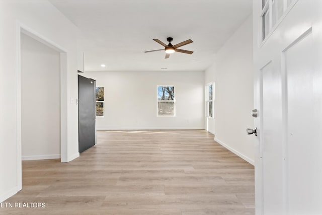 unfurnished room with baseboards, ceiling fan, and light wood finished floors