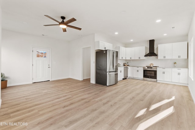 kitchen featuring stainless steel appliances, wall chimney range hood, backsplash, and light wood-style flooring