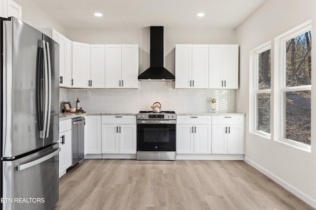 kitchen featuring wall chimney exhaust hood, white cabinetry, and stainless steel appliances