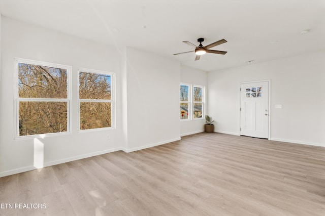 spare room with light wood-type flooring, ceiling fan, and baseboards