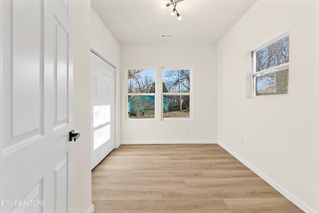 unfurnished room featuring a healthy amount of sunlight, visible vents, baseboards, and light wood finished floors