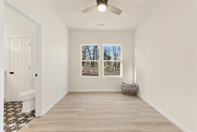 interior space featuring baseboards, ceiling fan, visible vents, and light wood-style floors