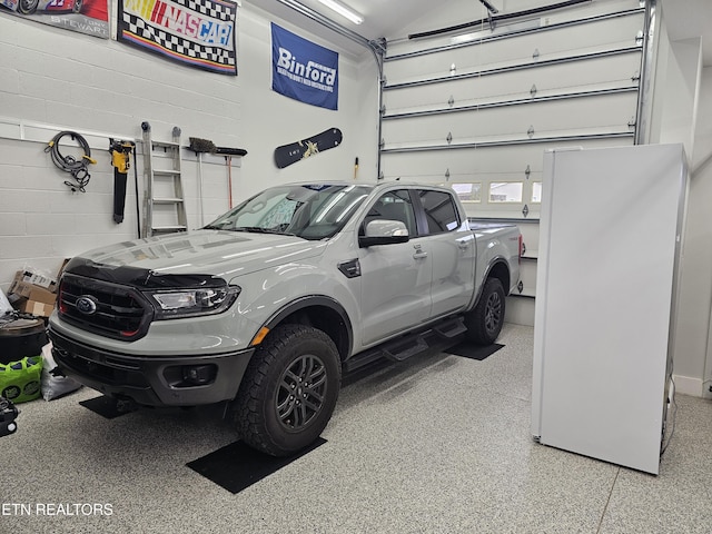 garage with freestanding refrigerator and concrete block wall