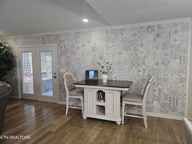 dining area featuring a textured ceiling, wood finished floors, baseboards, ornamental molding, and wallpapered walls