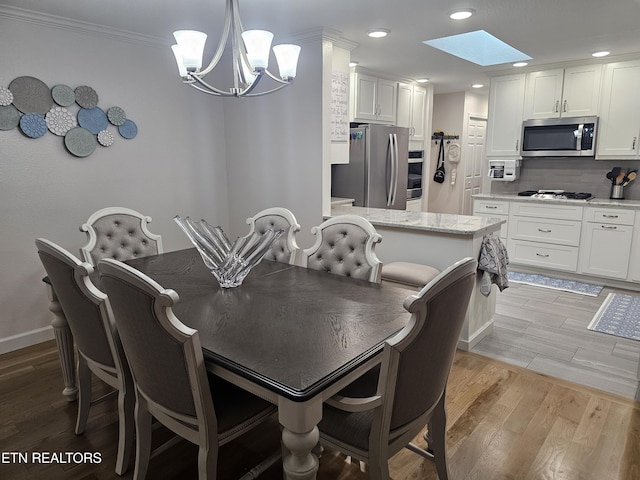 dining space with a skylight, crown molding, recessed lighting, an inviting chandelier, and light wood-type flooring