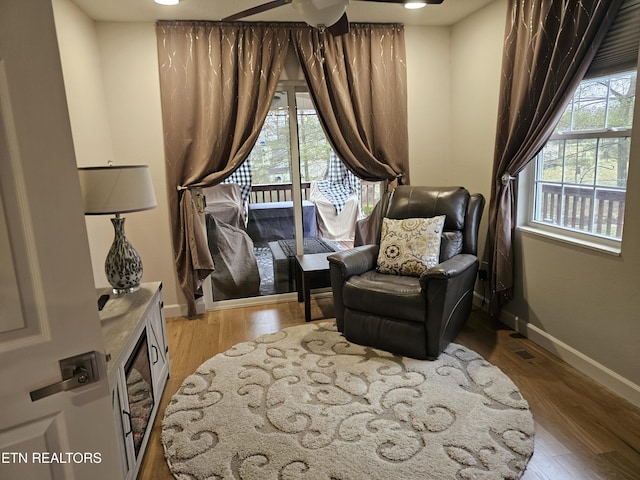 living area with ceiling fan, wood finished floors, and baseboards