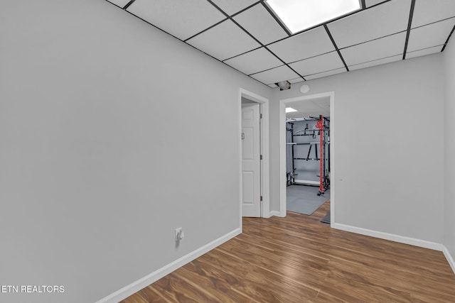 empty room with a paneled ceiling, baseboards, and wood finished floors