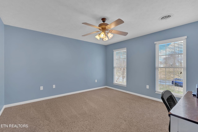 unfurnished office featuring a ceiling fan, carpet, visible vents, and baseboards