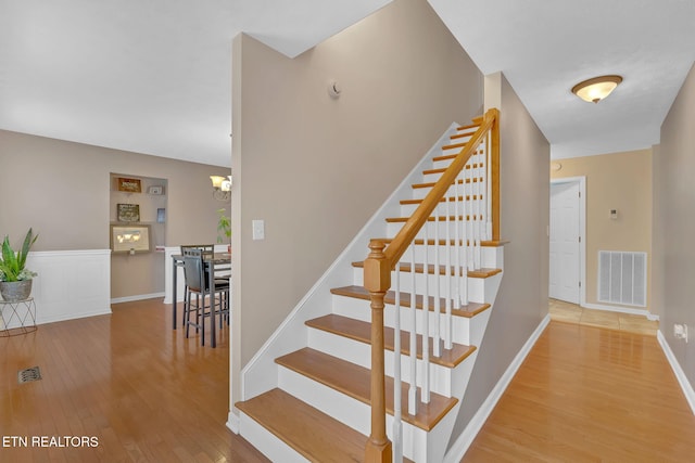 staircase with visible vents, baseboards, and wood finished floors