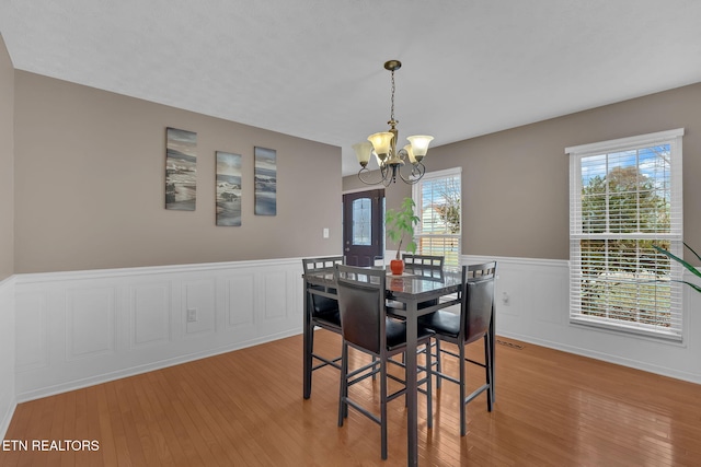 dining room with a wainscoted wall, hardwood / wood-style flooring, and a notable chandelier