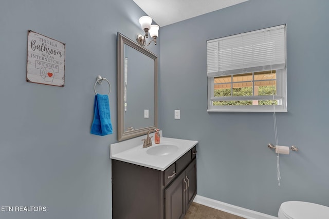 bathroom with baseboards, vanity, and toilet