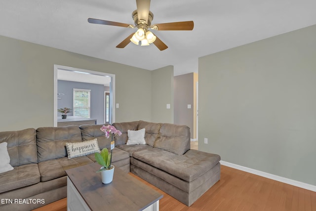 living room featuring baseboards, a ceiling fan, and light wood-style floors