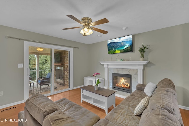 living room featuring visible vents, a ceiling fan, wood finished floors, a tile fireplace, and baseboards