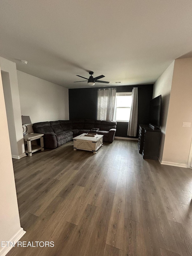 living area featuring dark wood-style flooring, a ceiling fan, and baseboards