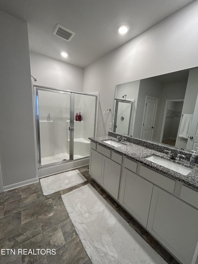 full bath featuring double vanity, a stall shower, visible vents, and a sink