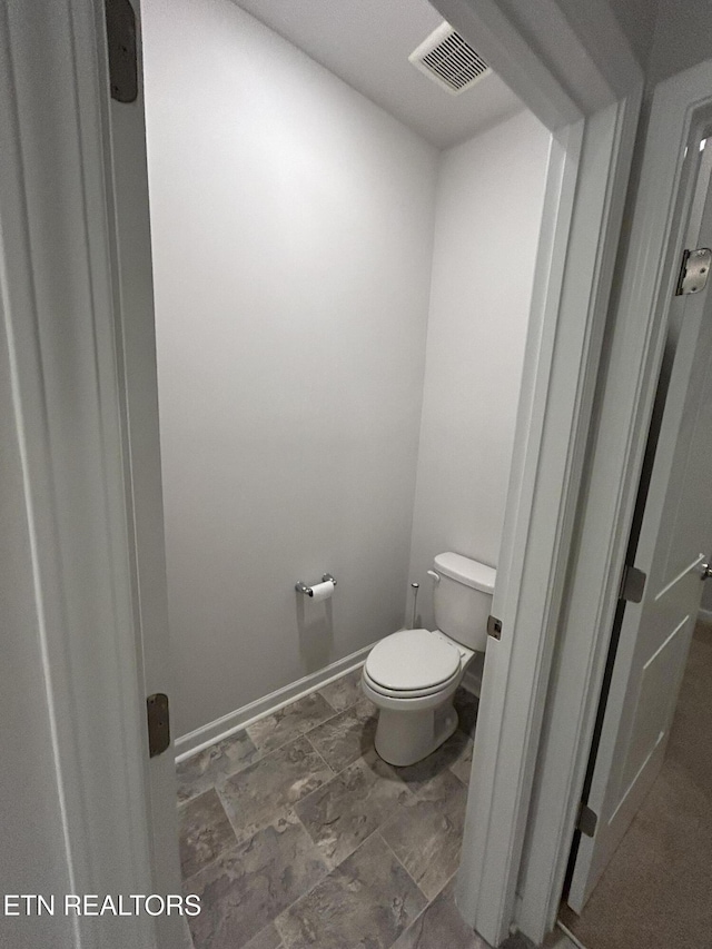 bathroom featuring toilet, visible vents, and baseboards