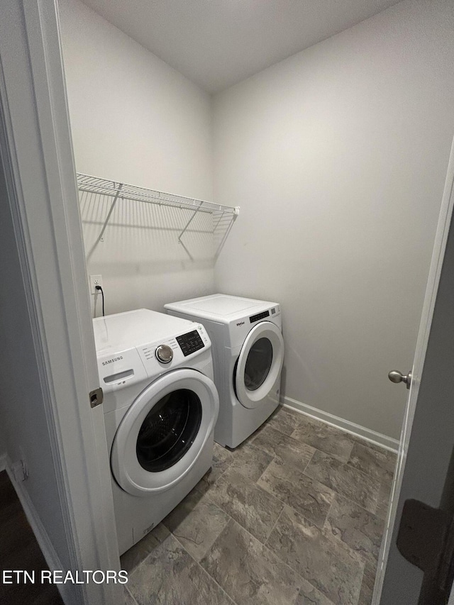 laundry room with laundry area, stone finish flooring, baseboards, and washer and dryer