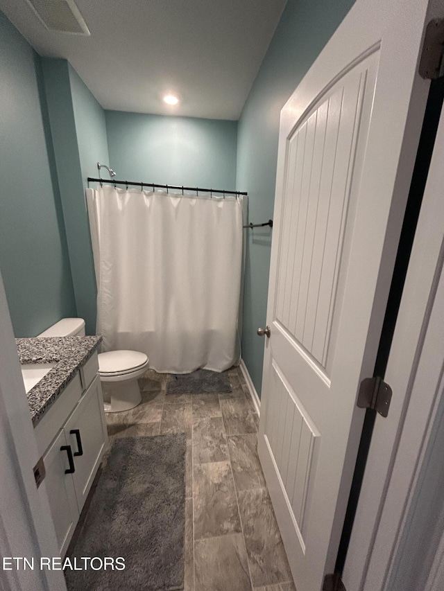 full bath with toilet, visible vents, vanity, and baseboards