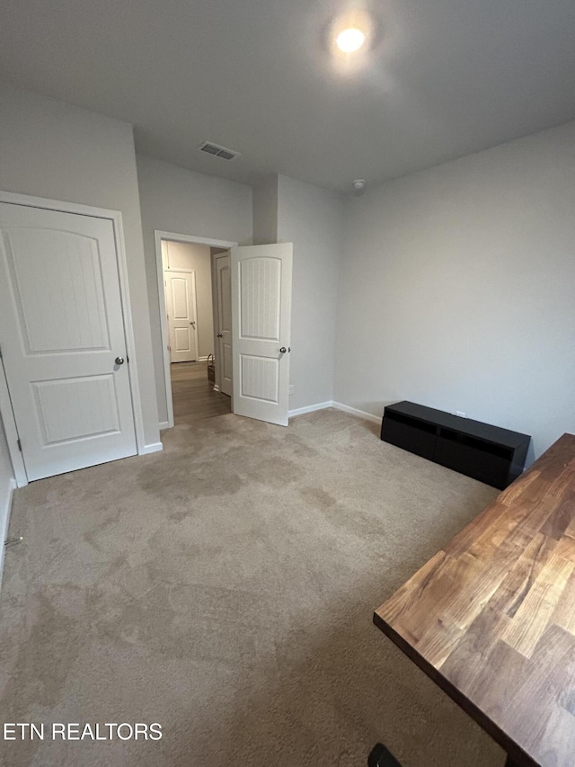 unfurnished bedroom featuring carpet floors, visible vents, and baseboards