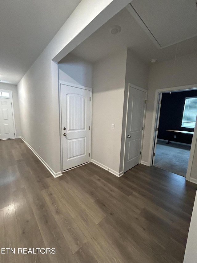 interior space featuring attic access, dark wood-style flooring, and baseboards