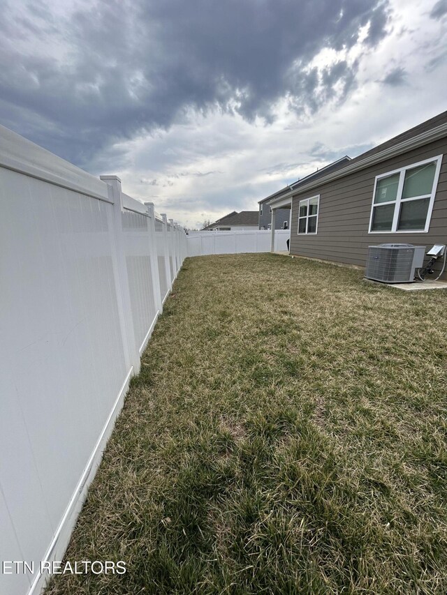 view of yard with a fenced backyard and central AC