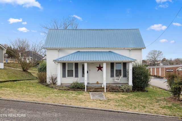 view of front of property featuring covered porch, metal roof, and a front yard