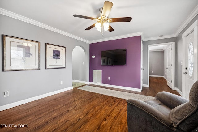 unfurnished living room featuring arched walkways, visible vents, ornamental molding, wood finished floors, and baseboards