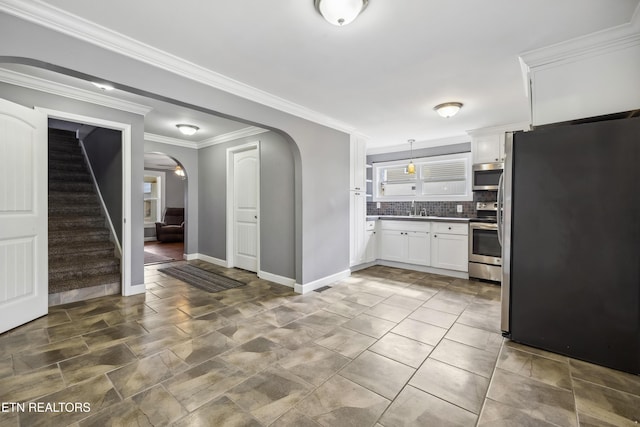 kitchen featuring white cabinets, appliances with stainless steel finishes, arched walkways, and a sink