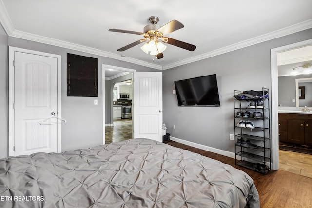 bedroom featuring baseboards, arched walkways, ceiling fan, ornamental molding, and wood finished floors