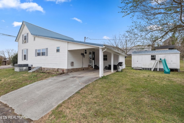 rear view of property with an outbuilding, a lawn, a storage shed, and central AC unit