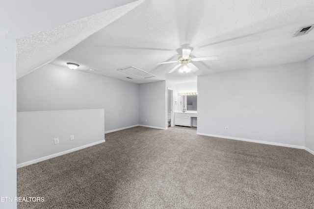 interior space with visible vents, baseboards, attic access, carpet flooring, and a textured ceiling