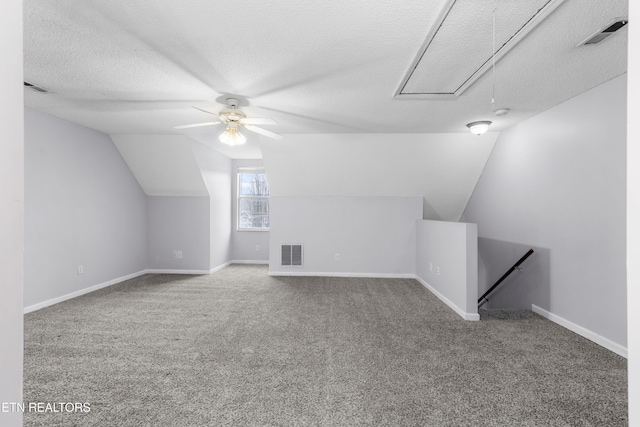 additional living space with attic access, carpet flooring, visible vents, and a textured ceiling