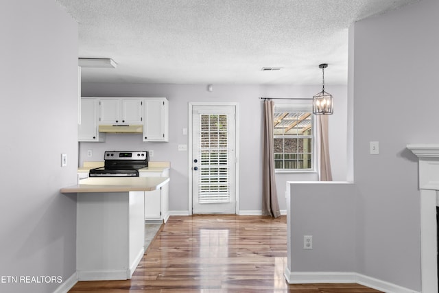 kitchen with stainless steel electric range oven, white cabinets, light countertops, and under cabinet range hood