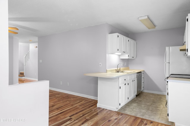kitchen featuring light wood finished floors, a sink, light countertops, range with electric stovetop, and white cabinetry
