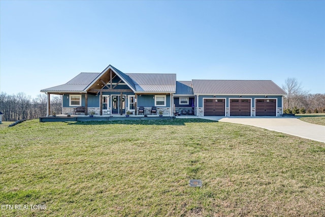 view of front facade with metal roof, a garage, stone siding, concrete driveway, and a front yard