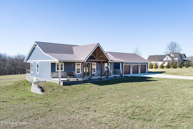 view of front facade with metal roof, an attached garage, driveway, and a front yard