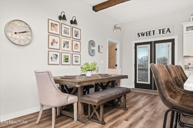 dining area featuring light wood-style flooring, baseboards, beamed ceiling, and french doors