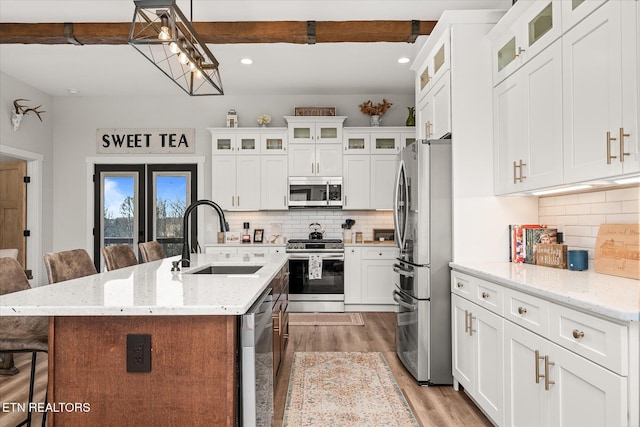 kitchen with a breakfast bar area, stainless steel appliances, a sink, light wood-type flooring, and decorative backsplash