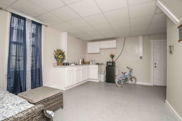 interior space with a paneled ceiling and baseboards