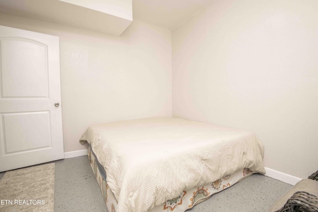 bedroom with finished concrete floors and baseboards