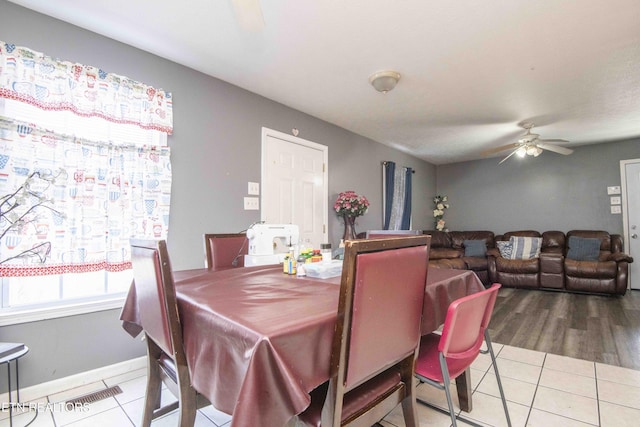 tiled dining space with a ceiling fan and baseboards