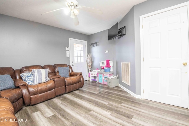 living room with baseboards, light wood-style flooring, visible vents, and a ceiling fan