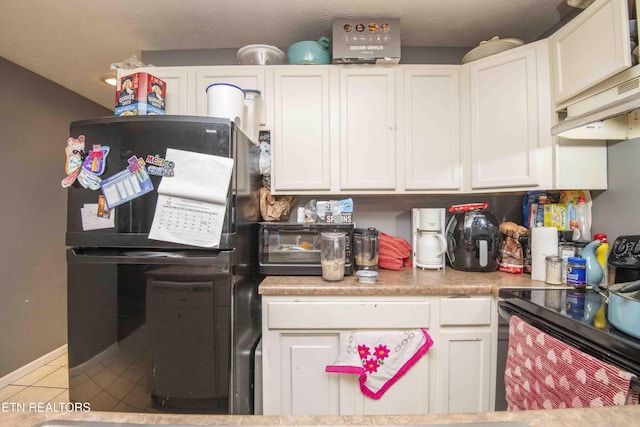 kitchen featuring a textured ceiling, tile patterned flooring, white cabinets, light countertops, and black appliances