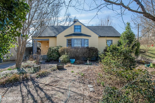 bungalow with a shingled roof and a chimney