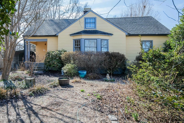 bungalow-style home featuring roof with shingles and a chimney