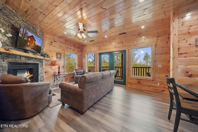 living area with plenty of natural light, a fireplace, wood ceiling, and wooden walls