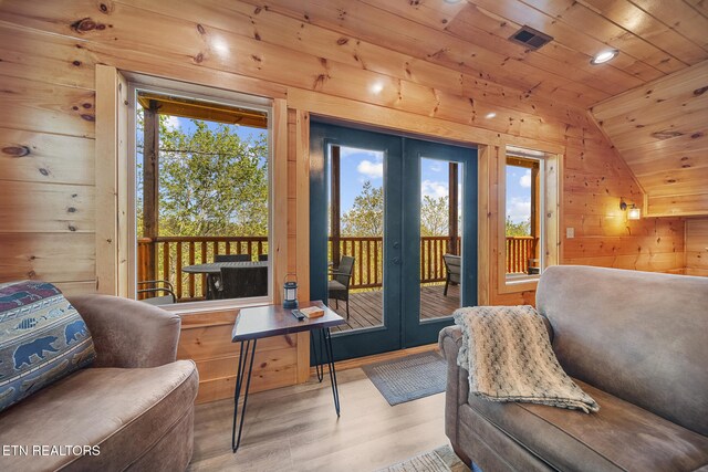 sitting room with wood walls, wood finished floors, wood ceiling, vaulted ceiling, and french doors