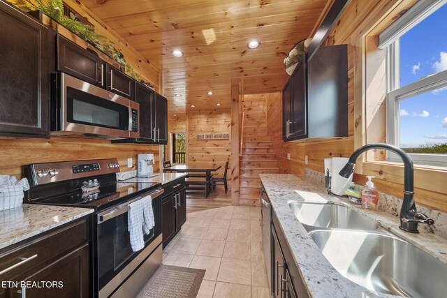 kitchen with wooden walls, wooden ceiling, appliances with stainless steel finishes, a sink, and recessed lighting